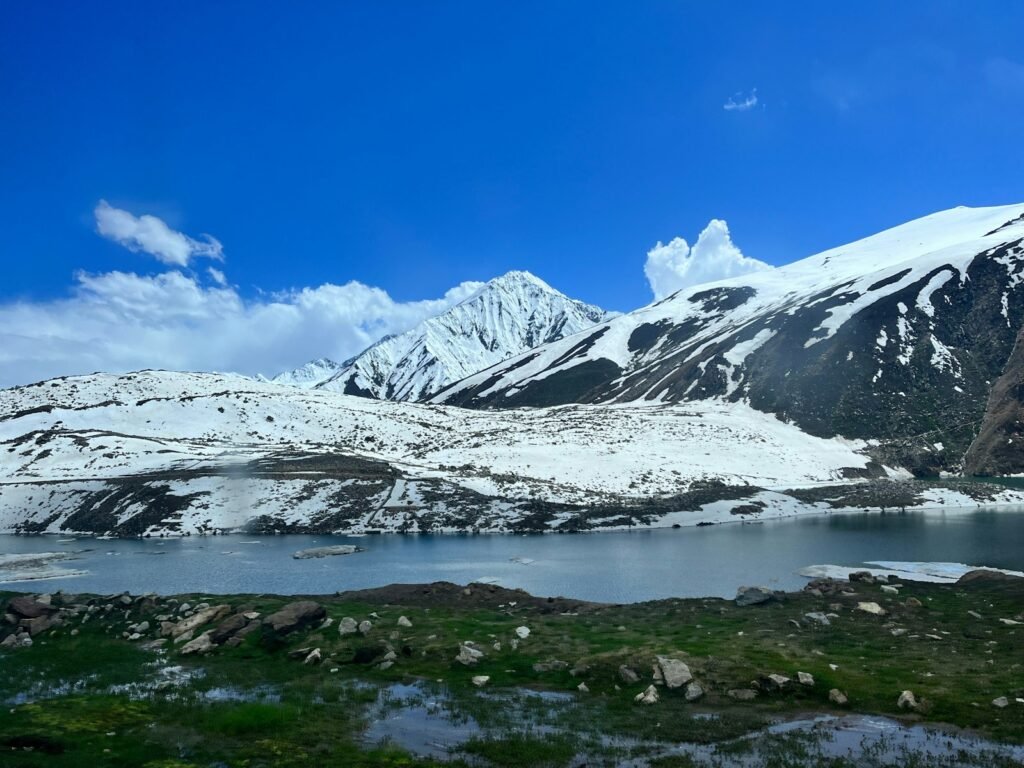 Snow-capped mountains overlook a clear blue lake.