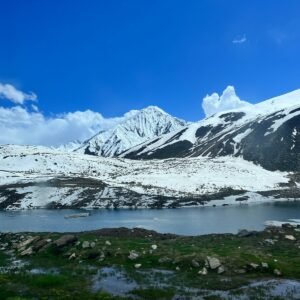 Snow-capped mountains overlook a clear blue lake.
