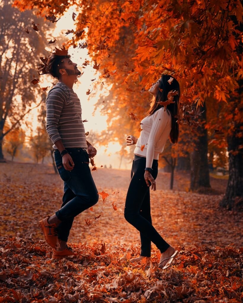 man and woman kissing on brown dried leaves during daytime
