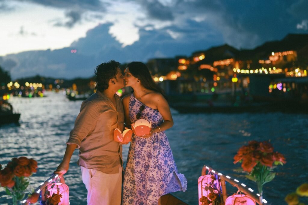 Couple kissing on a boat at night with lanterns.