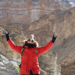 a woman standing on top of a mountain with her arms in the air