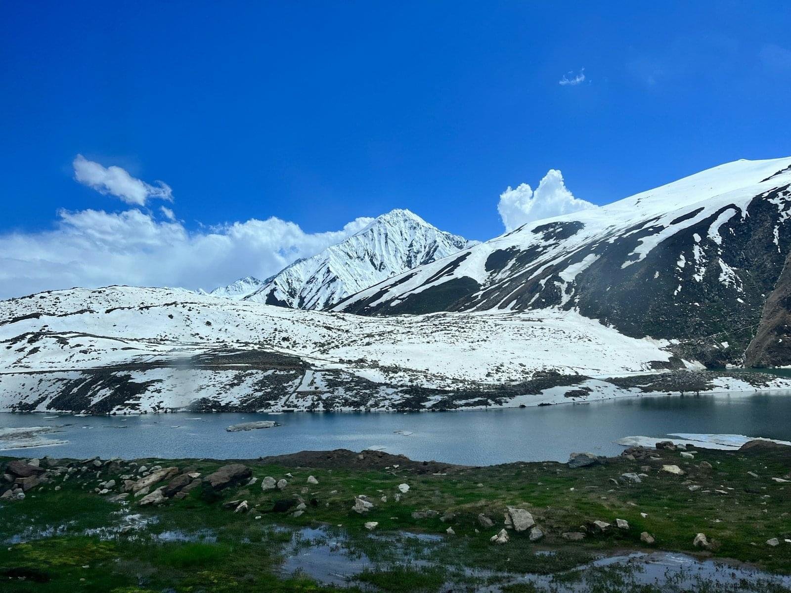 Snow-capped mountains overlook a clear blue lake.